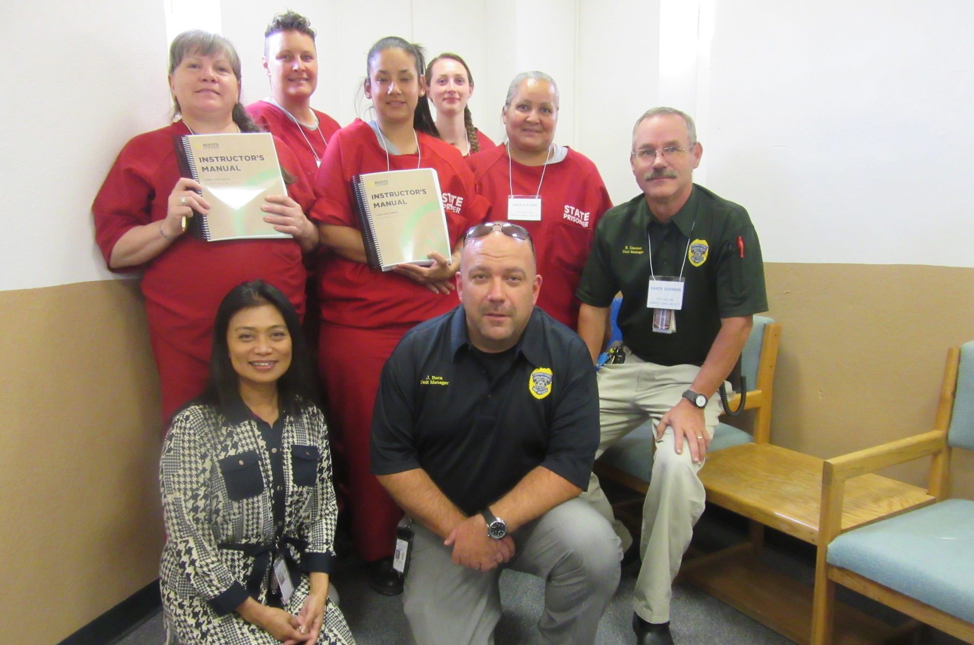 Female carceral students holding student workbooks along with carceral staff